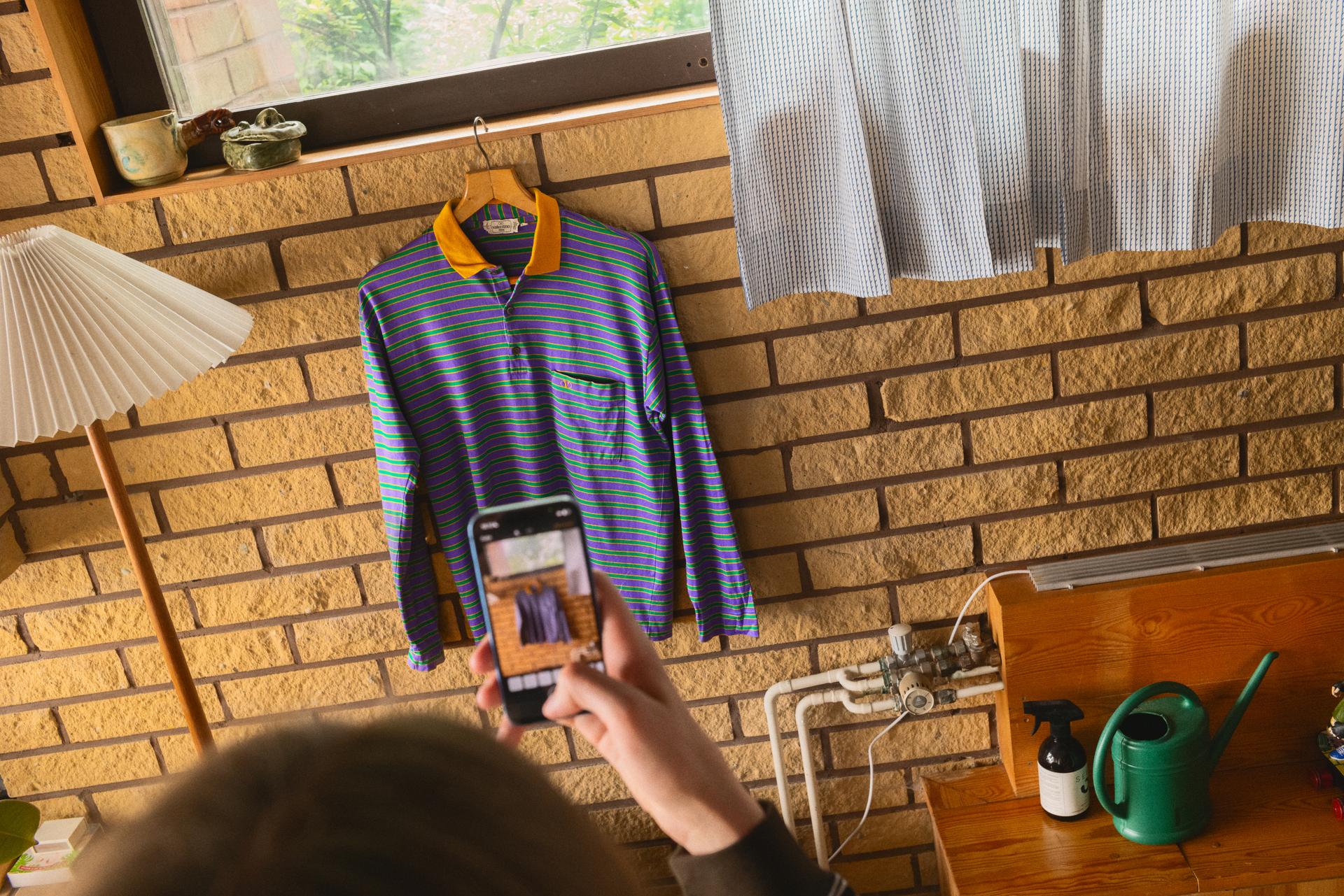 En person fotograferar en rutig skjorta med sin mobiltelefon.